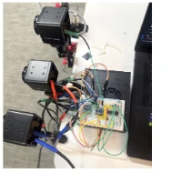 Two camera modules wired to a hand-built trigger board on the edge rig